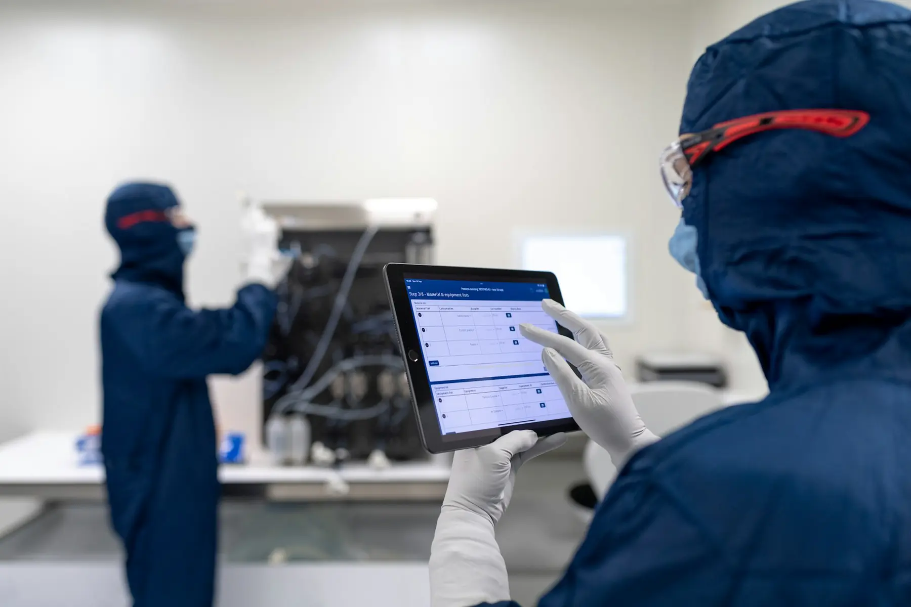 Techniciens consultant une tablette en salle blanche